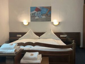 Standard-Doppelzimmer in der Aal-Kate Wuppertal mit Doppelbett, frischen Handtüchern, maritimer Dekoration und klassischem Holzmobiliar.