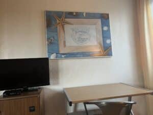 Schreibtisch mit Stuhl und Fernseher im Standard-Einzelzimmer der Aal-Kate Wuppertal, mit maritimer Wanddekoration und Tageslicht.