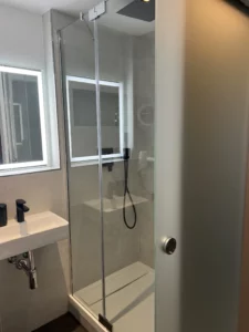 Moderne Dusche mit Glasabtrennung im Komfort-Einzelzimmer der Aal-Kate Wuppertal, ausgestattet mit Regenduschkopf und stilvollem Bad-Design.