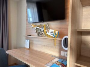 Schreibtisch im Komfort-Doppelzimmer der Aal-Kate Wuppertal mit Fernseher, maritimer Dekoration und Infomaterial zum Fischrestaurant.